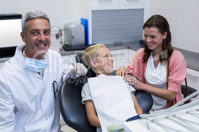 Mother and son talking while dentist examining