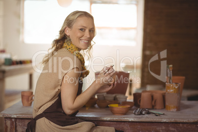 Beautiful female potter painting on pot