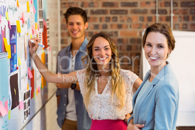 Business executive writing on sticky notes on whiteboard