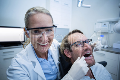 Female dentist examining male patient with tools