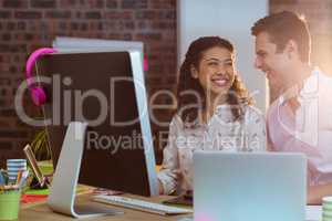 Businesswoman interacting with coworker while working on compute