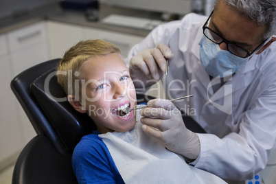 Dentist examining a young patient with tools