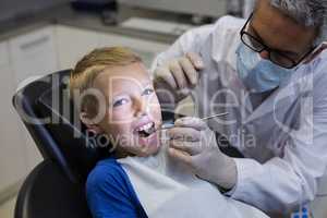 Dentist examining a young patient with tools