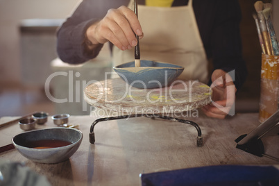 Male potter painting on bowl