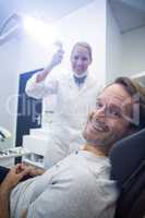 Female dentist and male patient smiling