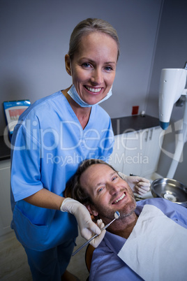 Smiling dentist examining a young patient with tools