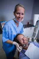 Smiling dentist examining a young patient with tools