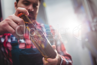 Male manufacturer examining beer bottle