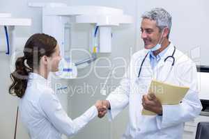 Dentist shaking hand with female patient