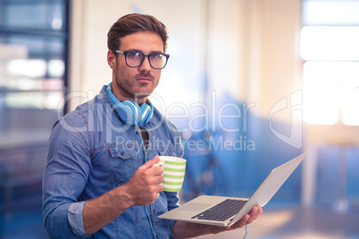 Business executive having coffee and holding a laptop