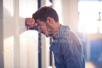 Tired businessman leaning on wall