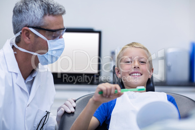 Dentist assisting young patient while brush teeth