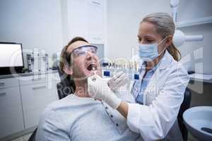 Female dentist examining male patient with teeth shades