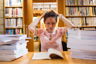 Tensed young woman studying in library