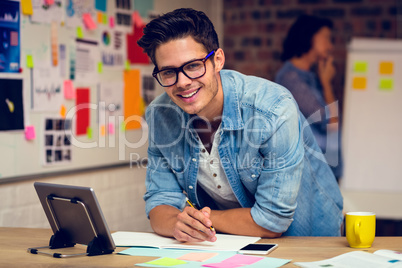 Business executive using digital tablet and taking notes in diar