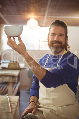 Potter holding bowl in workshop