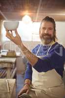 Potter holding bowl in workshop