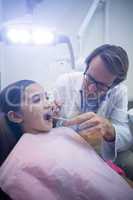 Dentist examining a young patient with tools