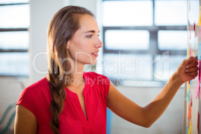 Woman putting sticky notes on whiteboard