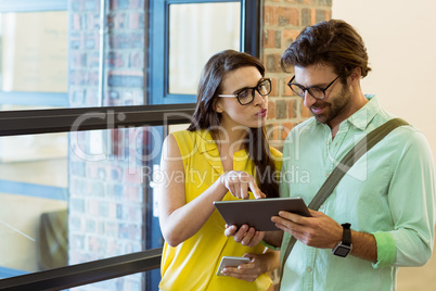 Business executive and co-worker interacting while using digital