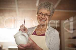 Female potter painting on jug