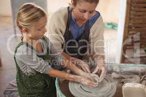 Female potter assisting girl