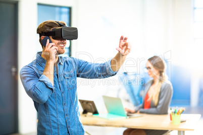 Young man using the virtual reality headset while talking on pho