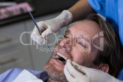 Dentist examining a young patient with tools