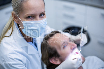 Dentist examining a patient with tools