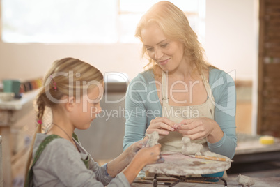 Smiling female potter assisting girls