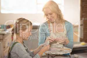 Smiling female potter assisting girls