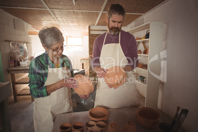 Male and female potter examining a pot
