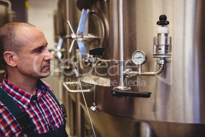 Manufacturer looking at pressure gauge in brewery