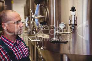 Manufacturer looking at pressure gauge in brewery