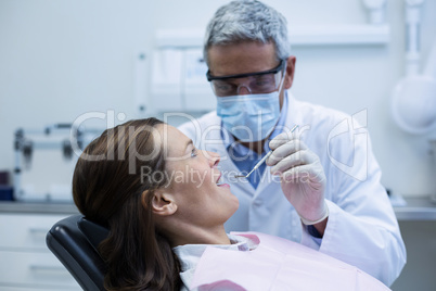 Dentist examining a young patient with tools