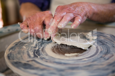 Close-up of potter removing clay from pottery wheel