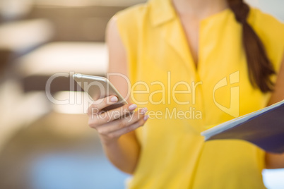Mid-section of female business executive using mobile phone