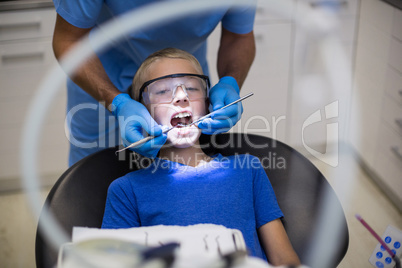 Dentist examining a young patient with tools