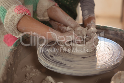 Girls making pot in pottery workshop