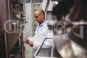 Manufacturer standing by storage tanks at brewery