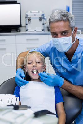 Dentist examining a young patient with tools