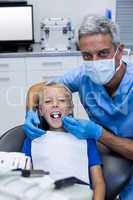 Dentist examining a young patient with tools