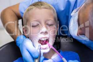 Dentist examining a young patient with tools