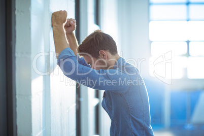 Tired businessman leaning on wall