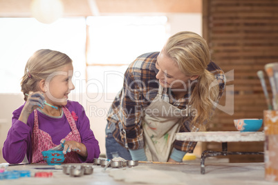 Female potter assisting girl in painting