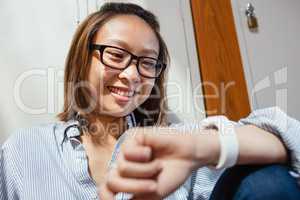 Happy young woman checking time on smartwatch in locker room