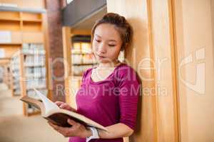 Young woman reading book in library