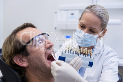 Female dentist examining male patient with teeth shades