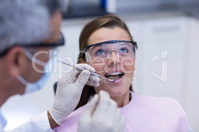 Dentist examining a female patient with tools