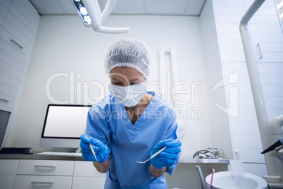 Dental assistant in surgical mask holding dental tools